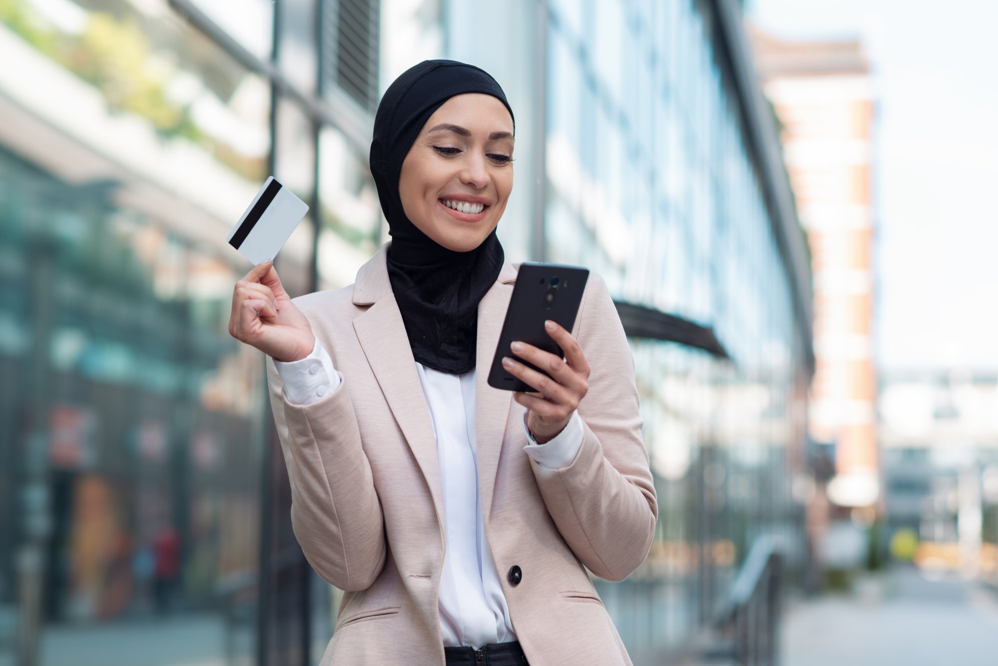 mujer-de-negocios-arabe-hablando-por-telefono-y-sosteniendo-una-tarjeta-de-credito-al-aire-libre (1)